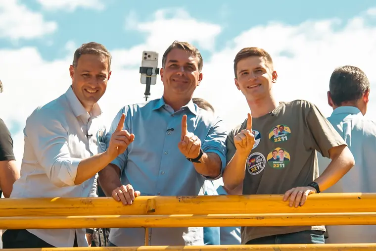 Lucas Pavanato com apoiadores em cima do trio, fazendo o sinal do número 1